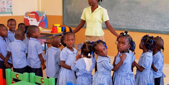 Niñas haitianas con profesora en clase. Foto OTC AECID Haití